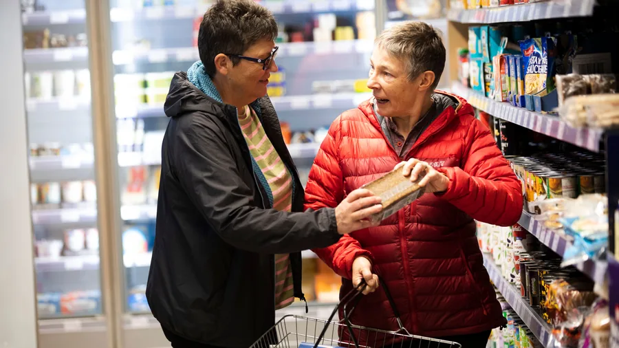Zwei ältere Menschen kaufen gemeinsam im Supermarkt ein Zwei ältere Menschen kaufen gemeinsam im Supermarkt ein